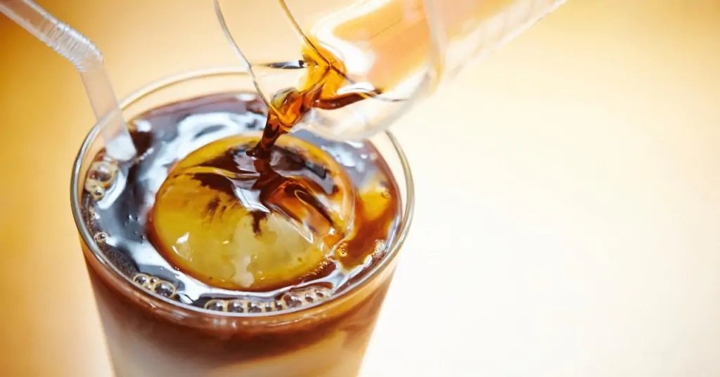 Pouring coffee syrup into an iced coffee drink