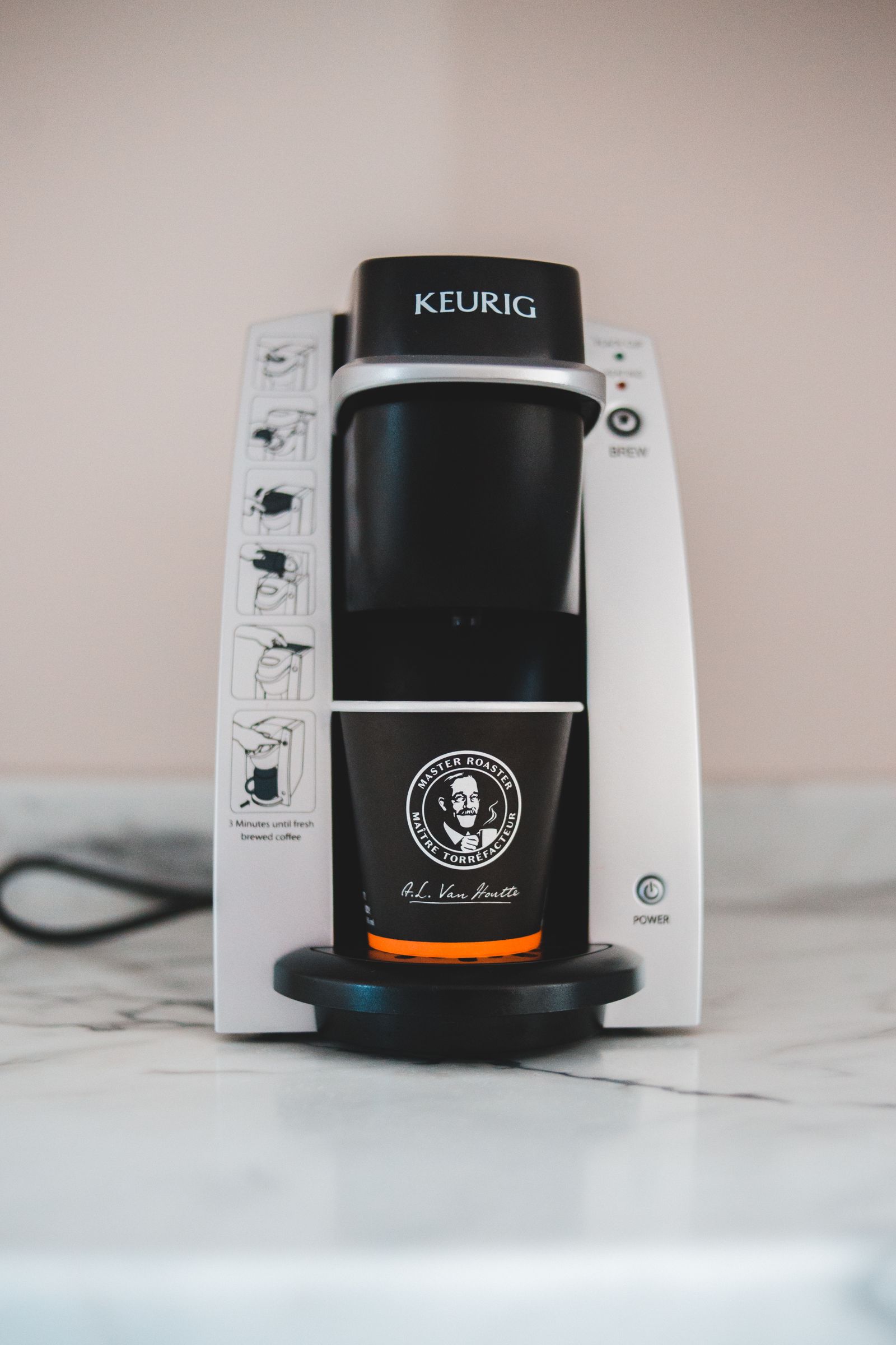 A Keurig brewer and coffee cup on a marble counter.